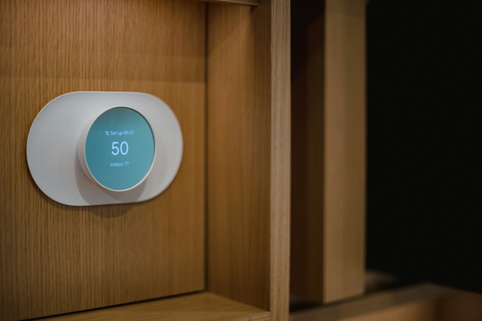 Round smart thermostat mounted on a wood-paneled wall