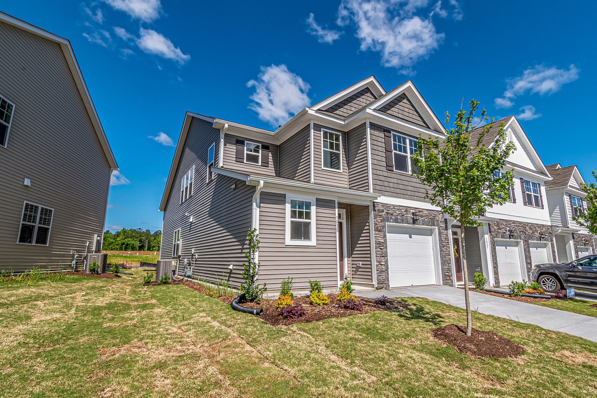 Two-story suburban home with a green lawn under a blue sky
